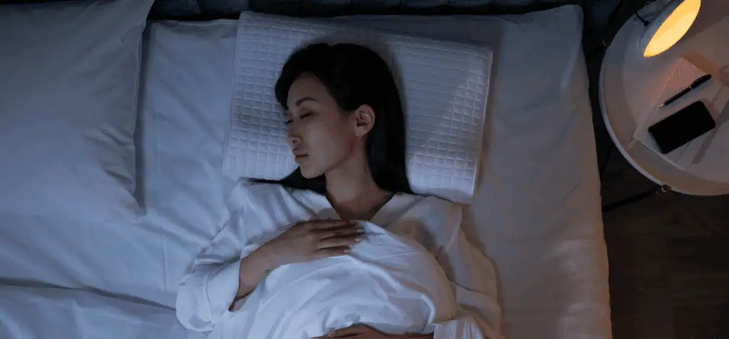 a woman lying in bed with her eyes closed